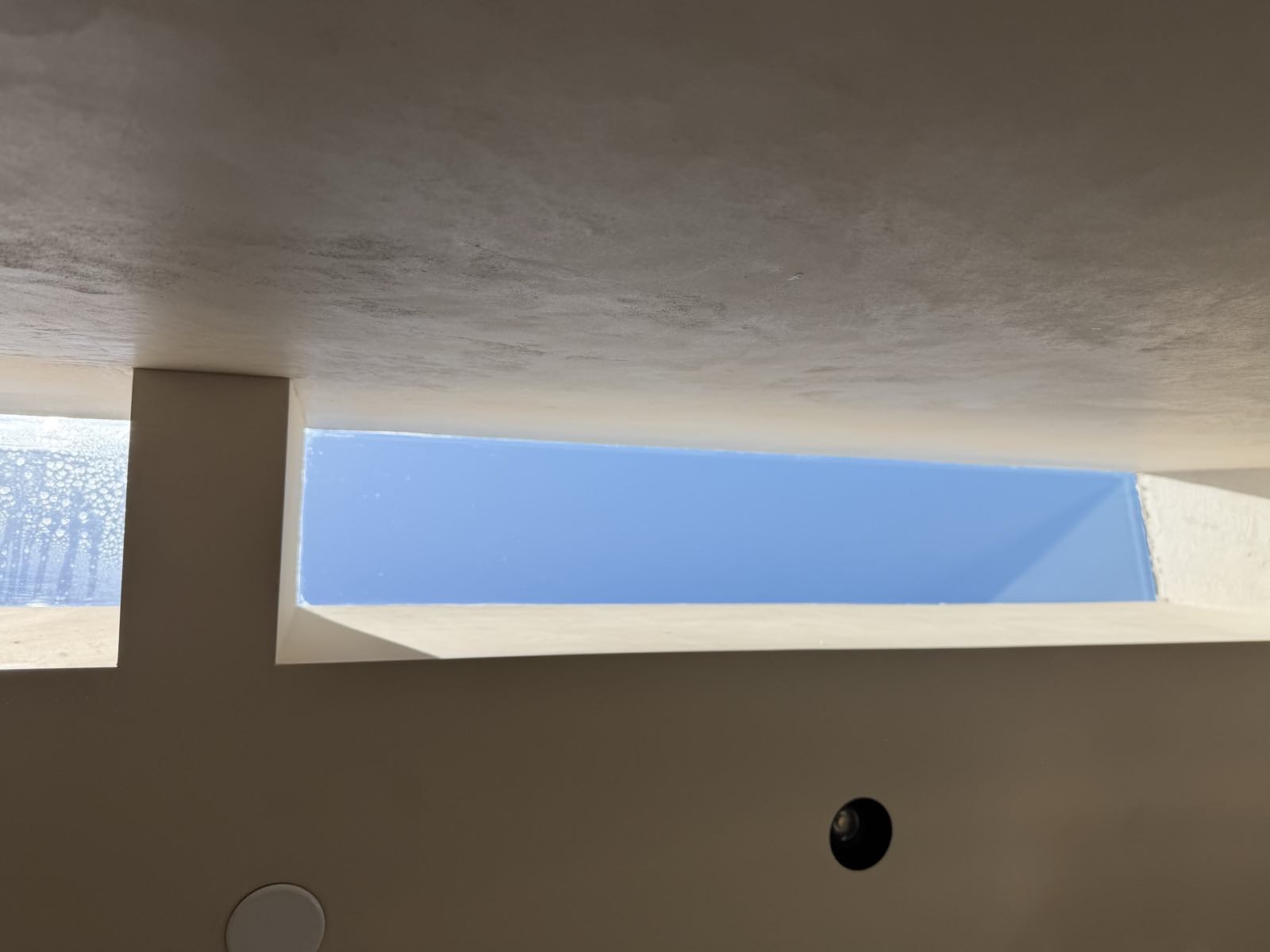 Slot skylight cleaned to invisible clarity during a post-construction clean, beside a honed limestone wall kept completely dry