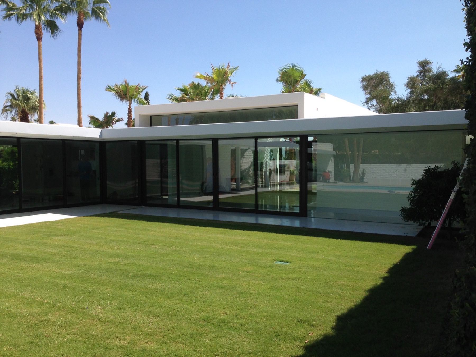 Estate home with expansive glass walls cleaned to a perfect shine, palms reflected in the windows