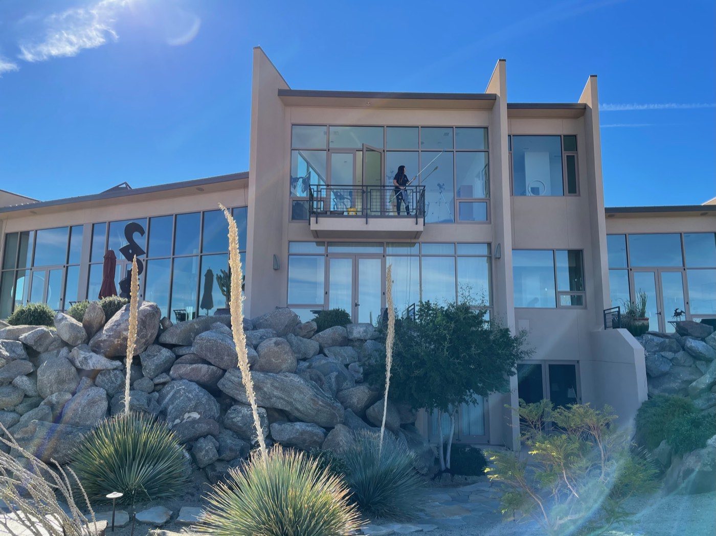 Technician cleaning tall estate windows with a water-fed pole at a Palm Desert area home