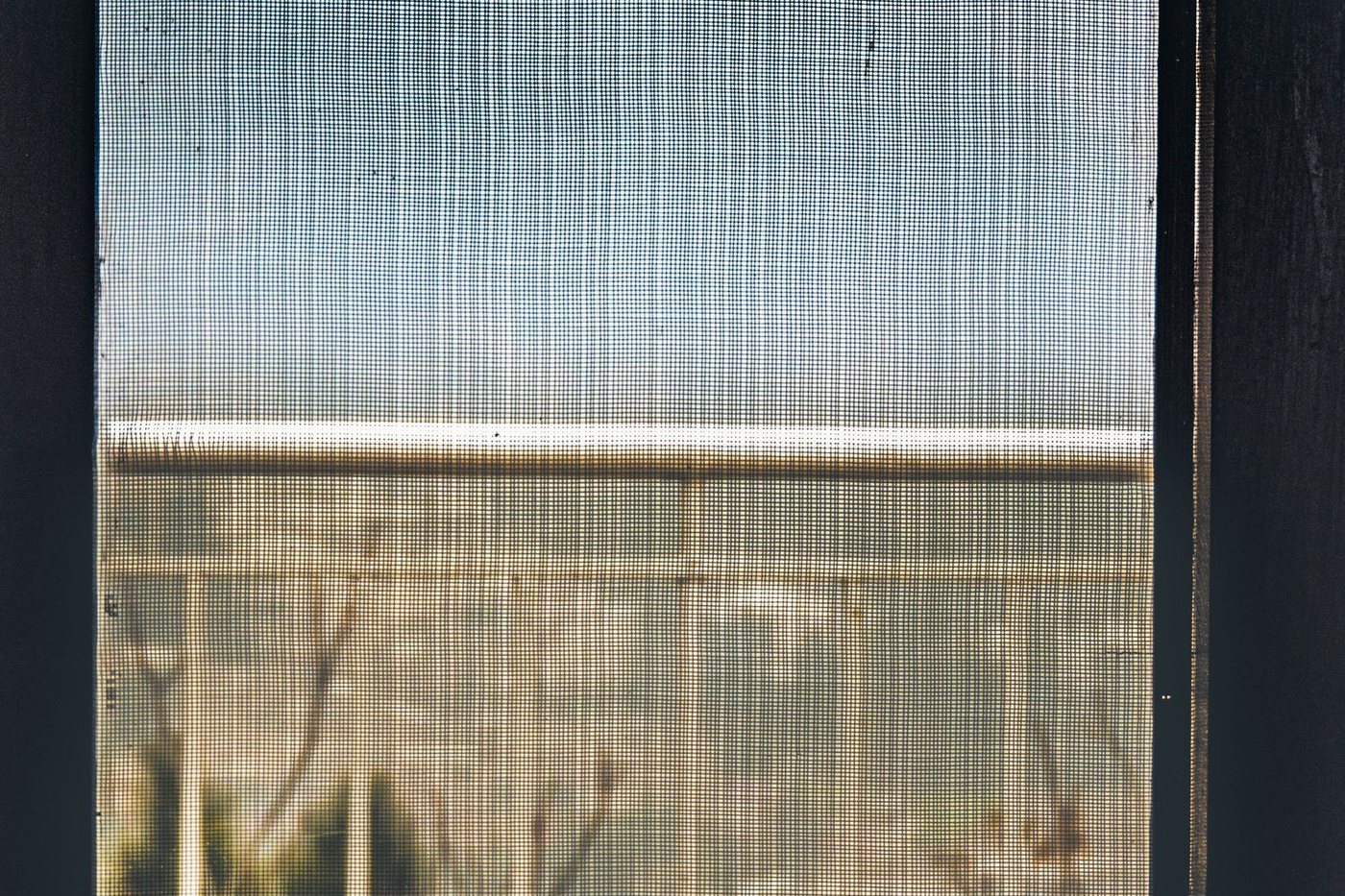 View through a window insect screen with the mesh dulled by dust