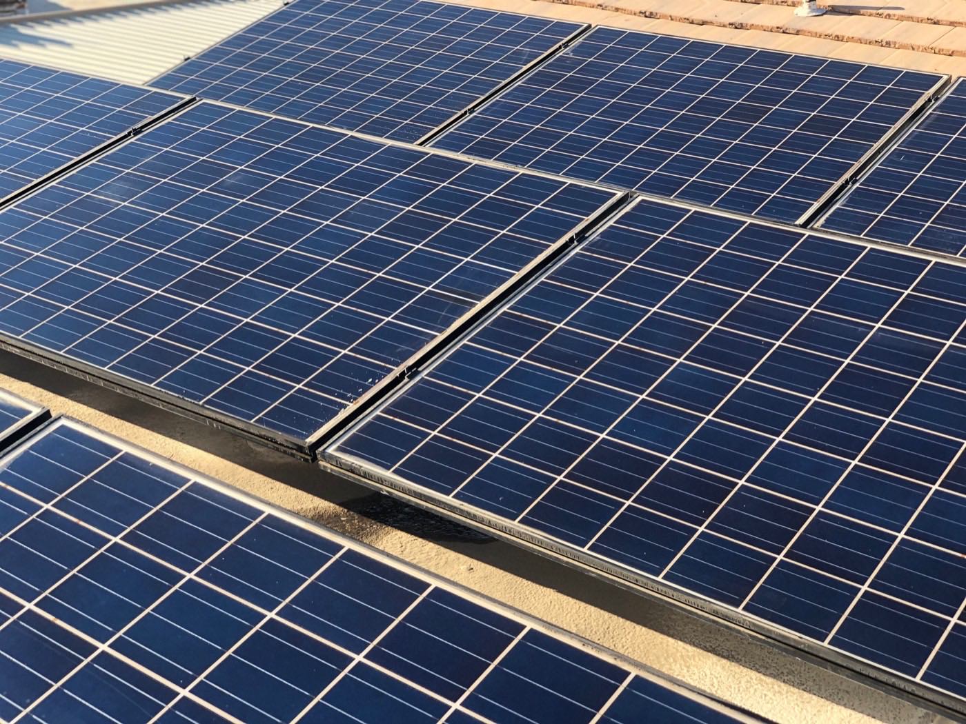 Rooftop solar panel array being cleaned of desert dust